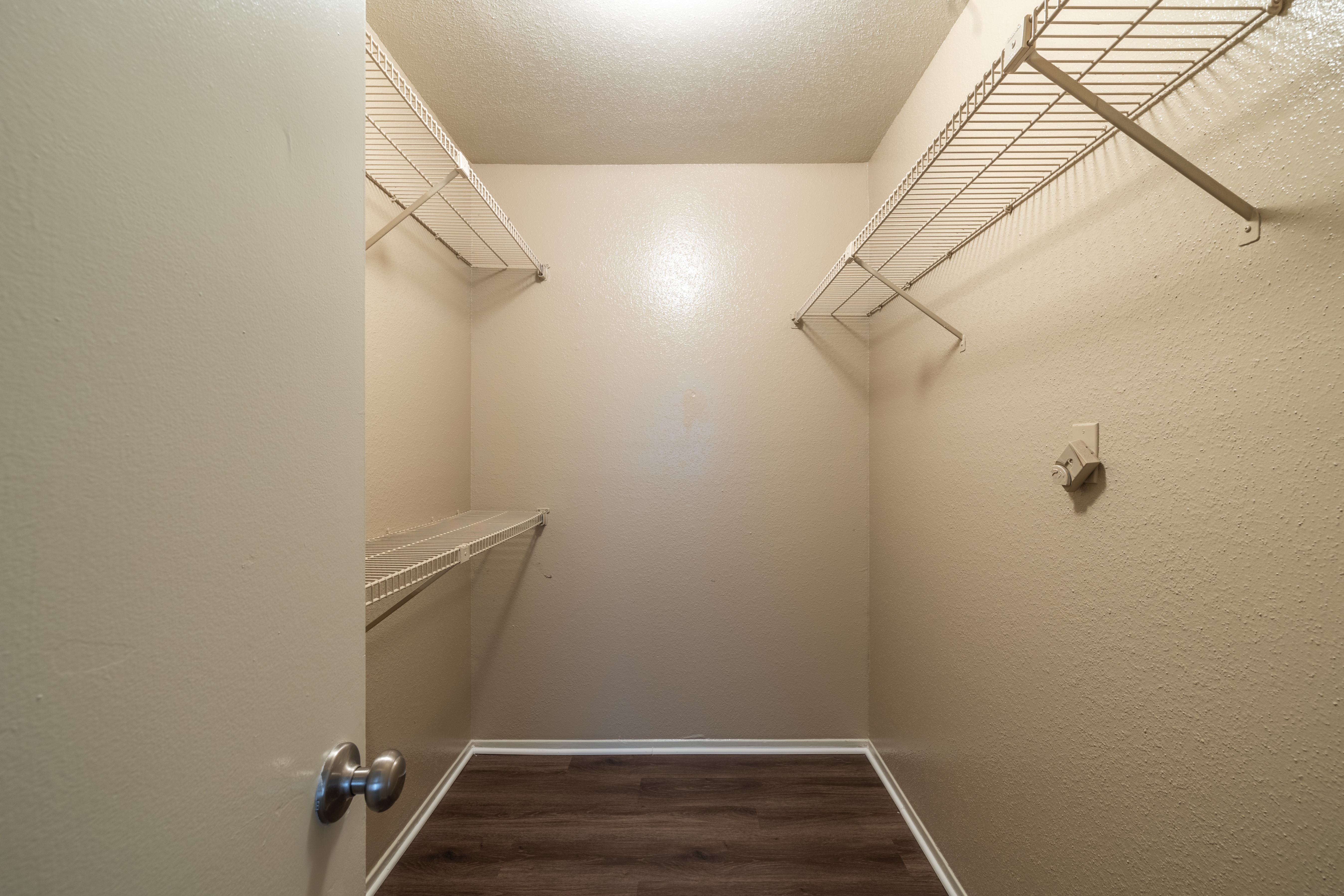 A walk-in closet with a white door and shelves.